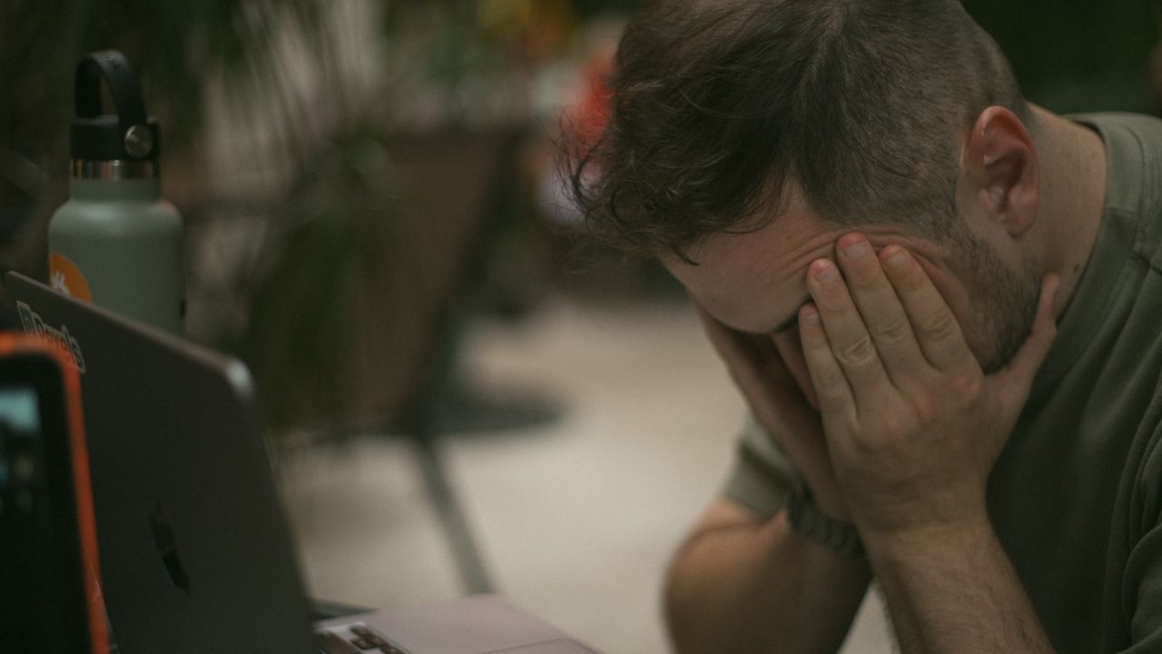 Mastering the First Impression: Your intriguing post title goes here Adult male appears stressed, sitting indoors with his hands on his face beside a laptop.